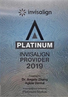 Aglow Plaque displaying 'Invisalign Platinum Provider 2019' certification, awarded to Dr. Angela Zhang of Aglow Dental. The background has a silver metallic texture with wavy lines, and the Invisalign logo is at the top.